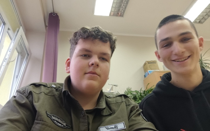 Dwóch młodych mężczyzn uśmiechających się do kamery w klasie.