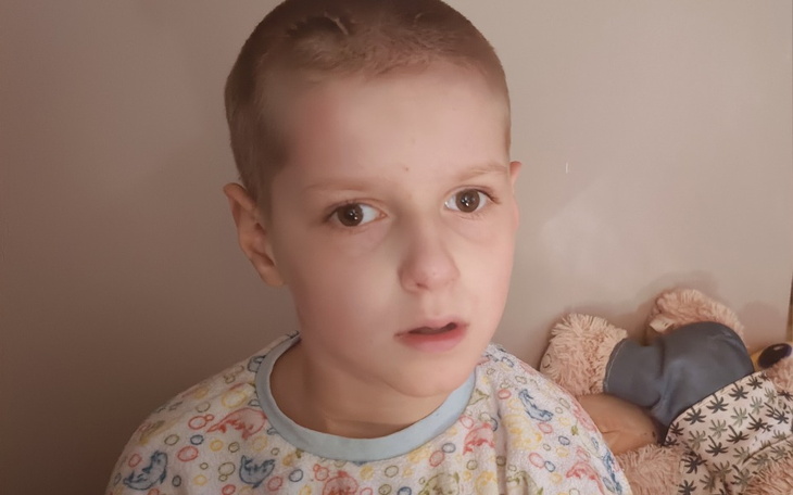 Chłopiec z poważnym wyrazem twarzy, w piżamie.