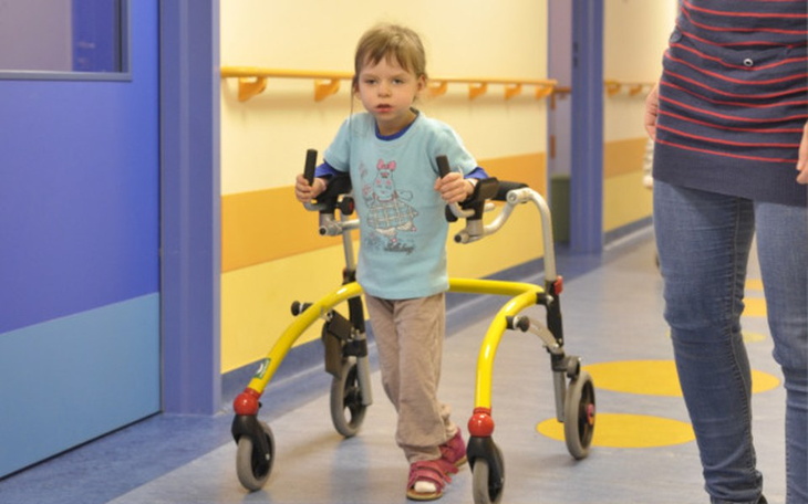 Dziecko korzystające z chodzika w szpitalnym korytarzu.