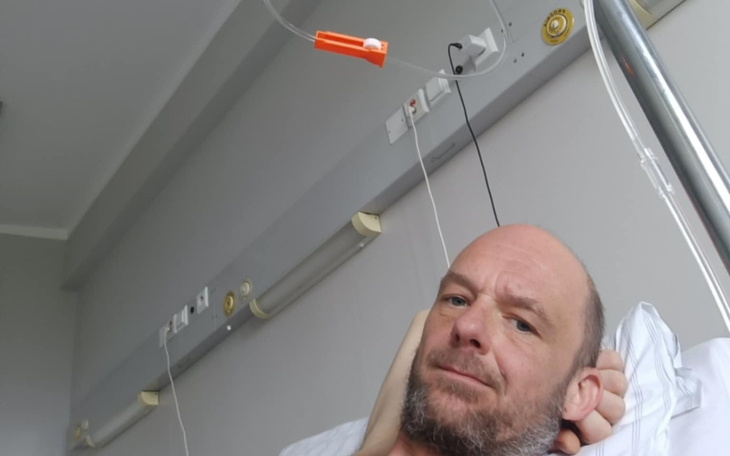 Mężczyzna leżący w szpitalnym łóżku, z kroplówką.