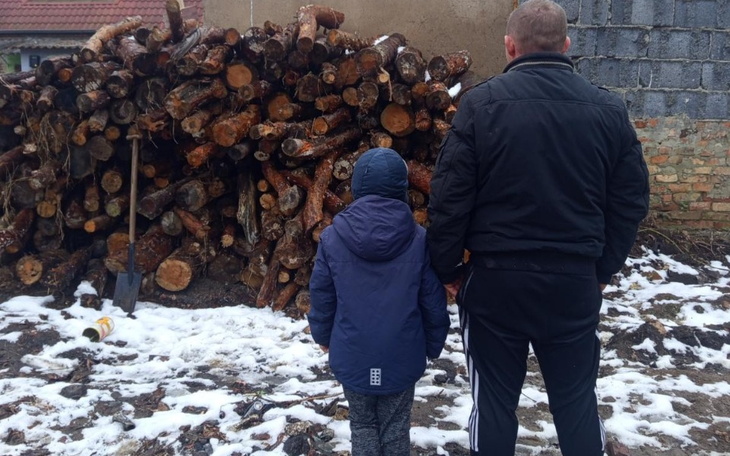 Dziecko i dorosły patrzący na stos drewna.
