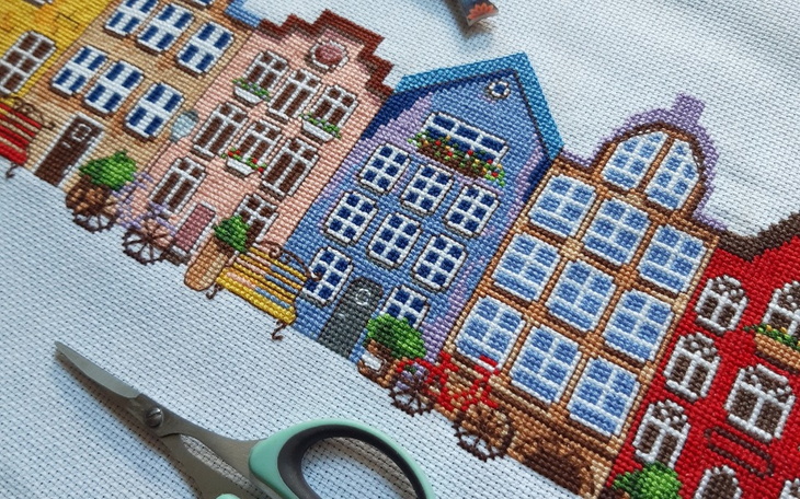 Wzór haftu przedstawiający kolorowe domy w mieście.