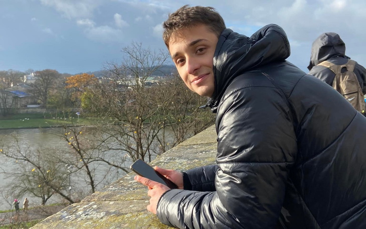 Mały kotek z biała plamką na piersi, w zieleni kwiatów.