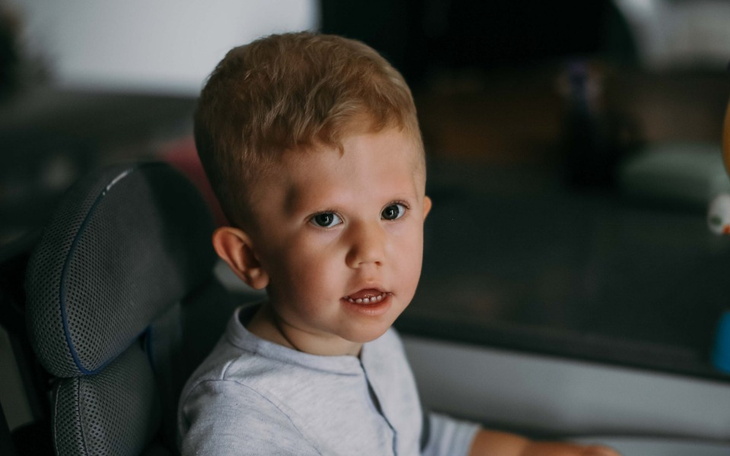 Mały chłopiec siedzący w krzesełku, uśmiechający się do kamery.