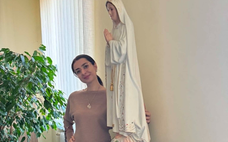 Młoda kobieta z kotem na krześle, tulą kota do twarzy.