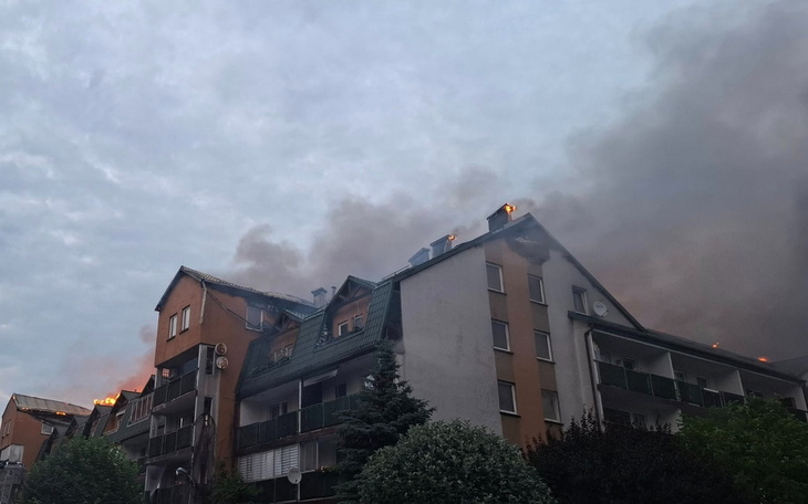 Pożar na dachu budynku mieszkalnego w szarym niebie.