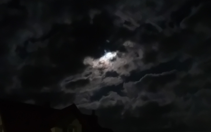 Nocne niebo z chmurami i księżycem, tworzącym tajemniczy klimat.