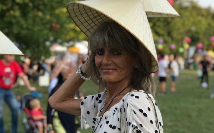 Kobieta w kapeluszu na festiwalu, uśmiechnięta wśród tłumu.