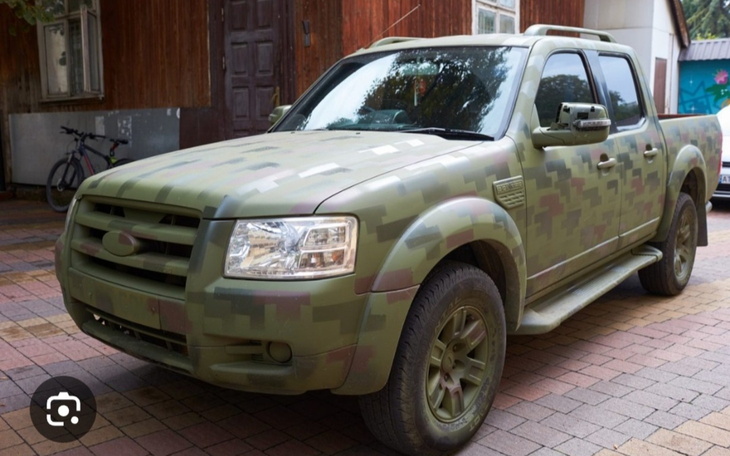 Samochód terenowy w kamuflażu zaparkowany na podjeździe.