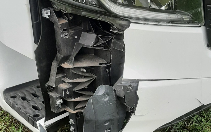 Uszkodzona część pojazdu, widoczna z bliska, z detalami uszkodzeń.
