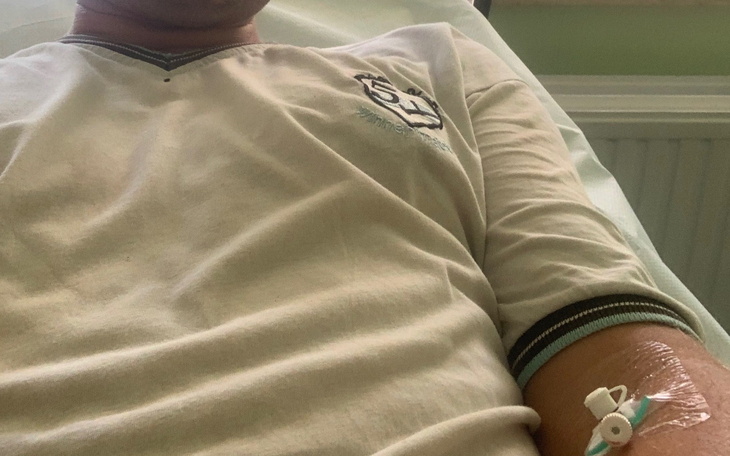 Osoba leżąca w szpitalnym łóżku z kroplówką.