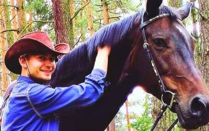 Mężczyzna głaszcze konia w lesie.