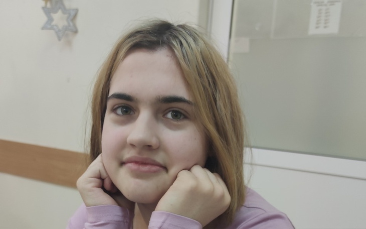 Młoda dziewczyna z rękami na twarzy, w jasnym otoczeniu.