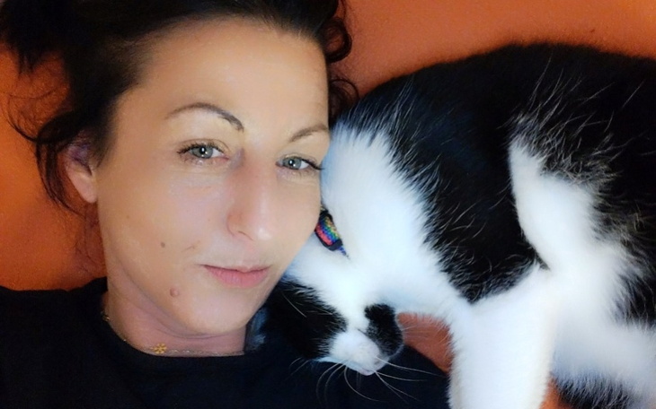 Kobieta leżąca z kotem, oboje wyglądają na zrelaksowanych i szczęśliwych.