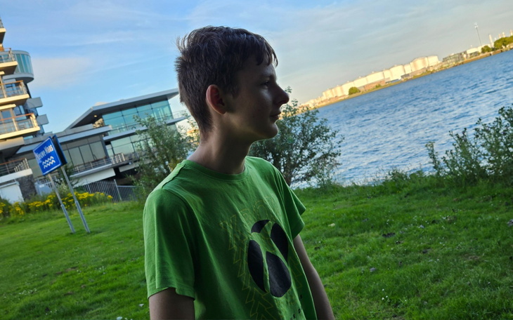 Chłopiec w zielonej koszulce na tle rzeki.