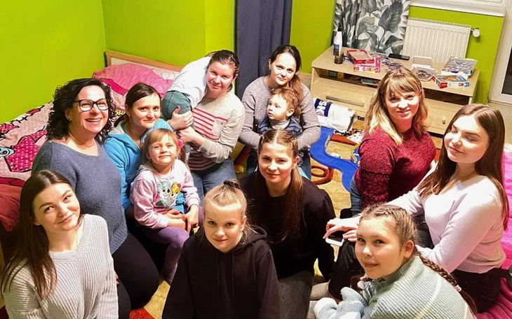 Grupa osób pozująca do zdjęcia w kolorowym pokoju.