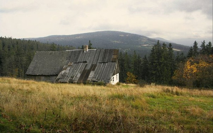 Stara, zniszczona chata na tle górskiego krajobrazu.