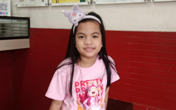 Dziewczynka w różowej koszulce z uśmiechem na twarzy.