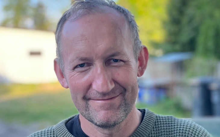 Mężczyzna uśmiechający się do kamery w plenerze.