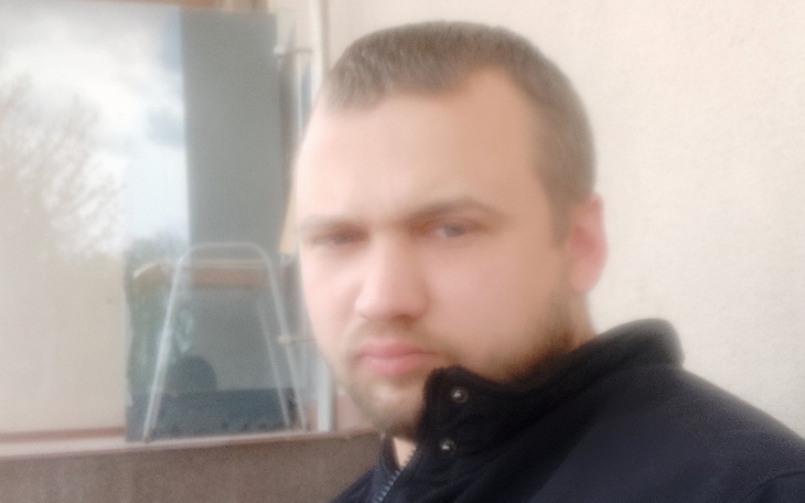 Mężczyzna z poważnym wyrazem twarzy, patrzy w obiektyw.