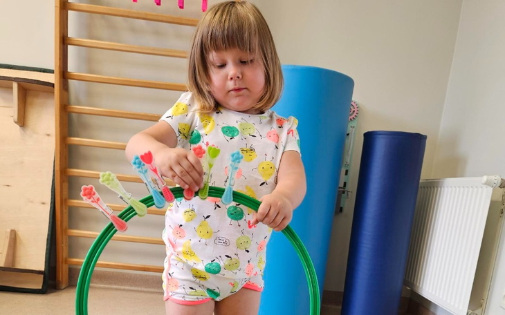 Mała dziewczynka bawi się kolorowymi kółkami w sali zabaw.