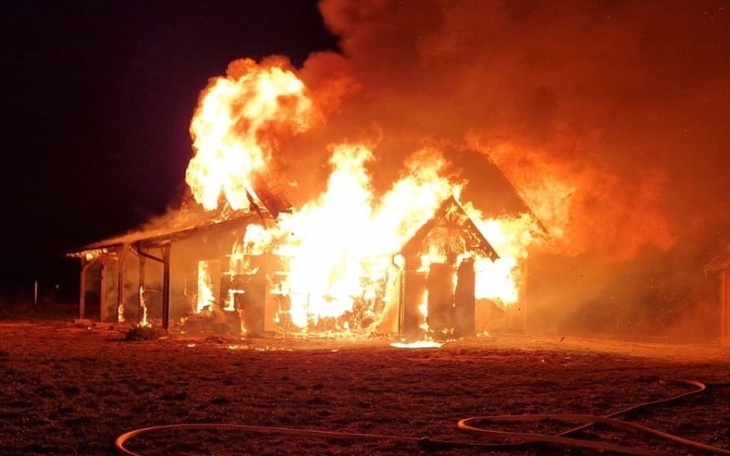 Pożar budynku, ogień trawi konstrukcję w nocy.