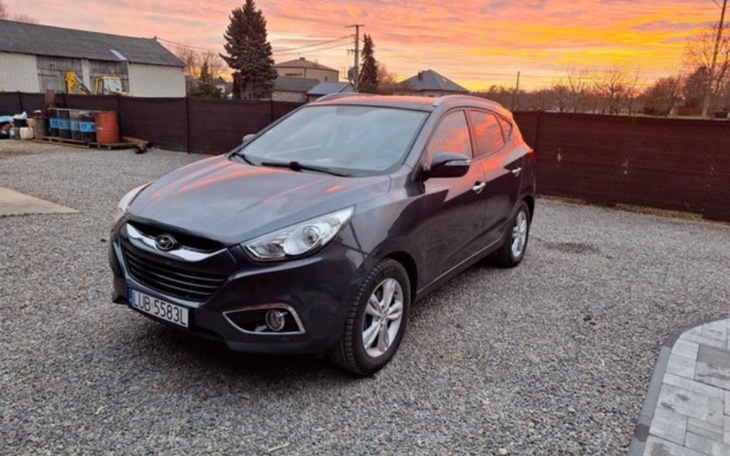 Samochód zaparkowany na podjeździe, w tle zachód słońca.