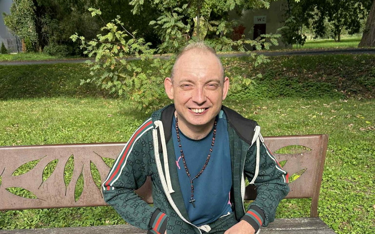 Mężczyzna uśmiechający się na ławce w parku.