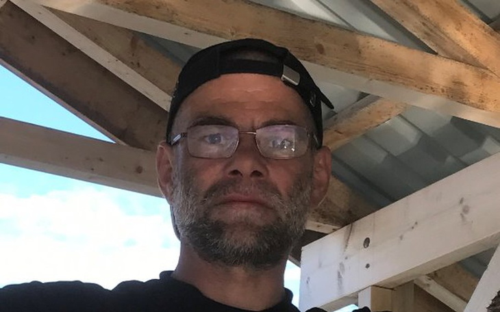 Mężczyzna w okularach i czapce, stojący w budynku.