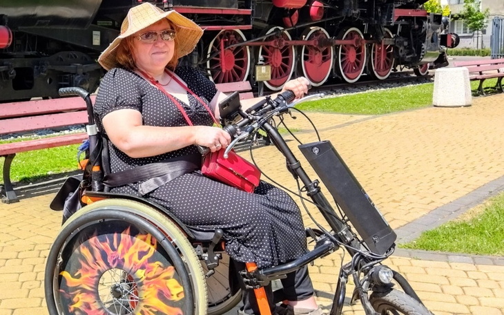 Kobieta na rowerze ręcznym w słomkowym kapeluszu.