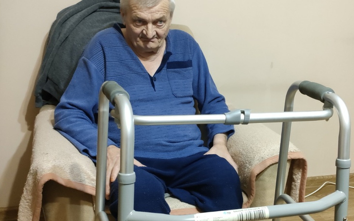 Starszy mężczyzna siedzący na fotelu z chodzikiem.