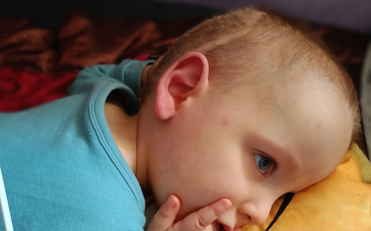 Małe dziecko leżące na poduszce, z zamyśloną miną.