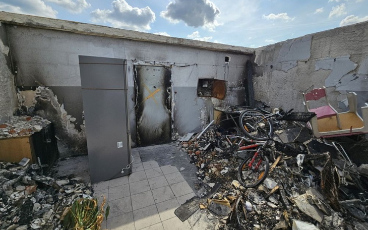 Zniszczone wnętrze po pożarze, z uszkodzonymi meblami i sprzętem.