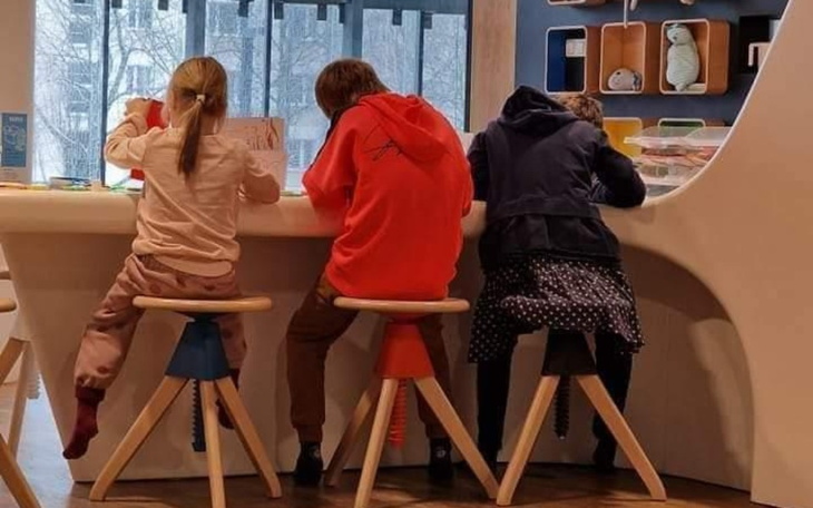 Trójka dzieci siedzących przy stole, skupionych na pracy.