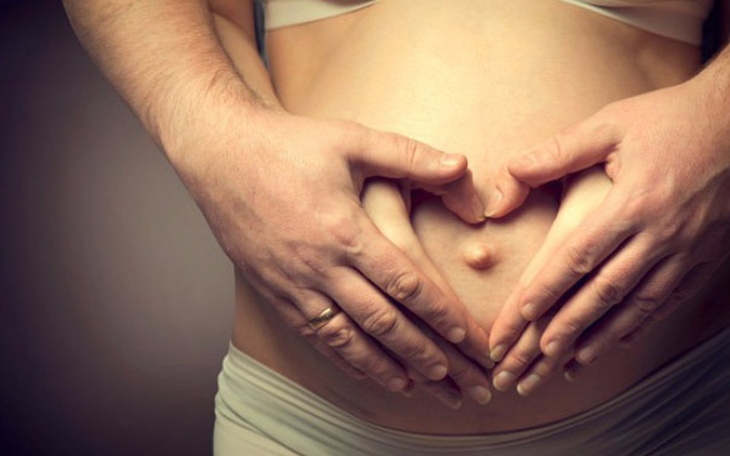 Dwie ręce tworzące serce na brzuchu ciężarnej kobiety.
