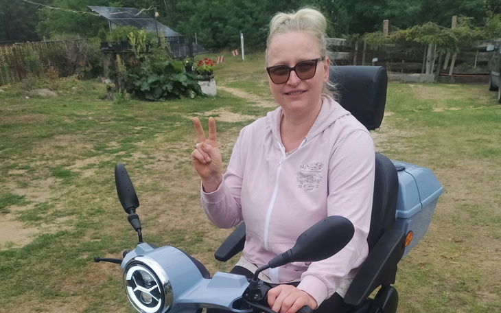 Kobieta na skuterze elektrycznym, uśmiechając się i pokazując znak pokoju.