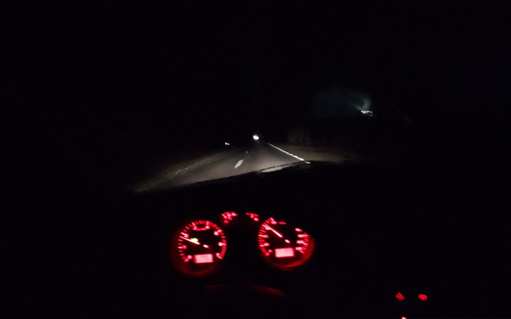 Widok na drogę nocą z podświetlonymi wskaźnikami.