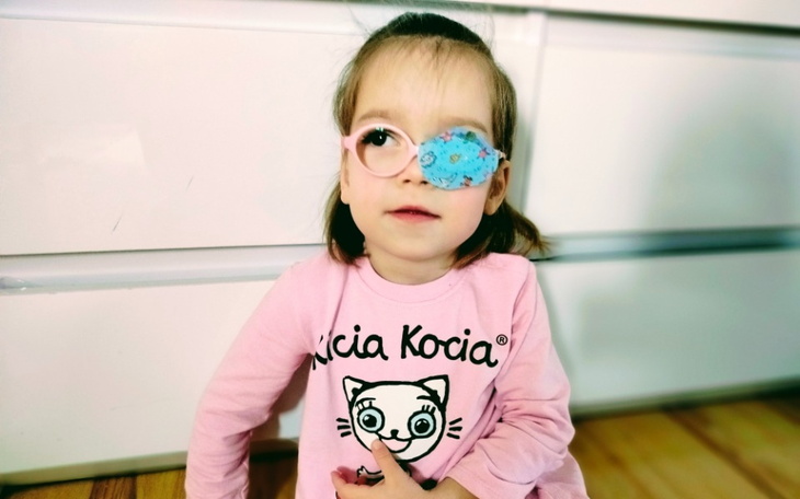 Mała dziewczynka w okularach, z opatrunkiem na oku.