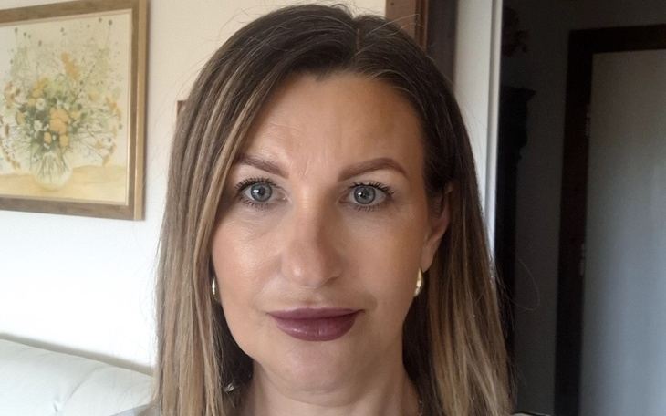 Kobieta z długimi włosami, uśmiecha się do kamery.