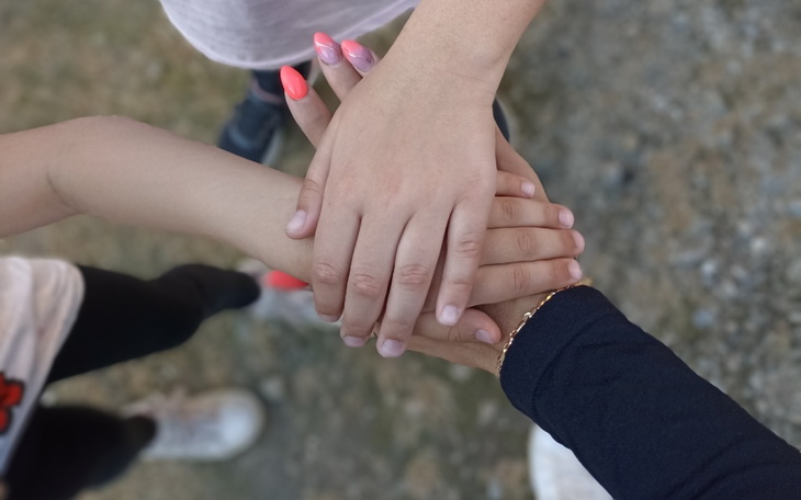 Ręce dzieci układające się w stos, symbolizujące współpracę.