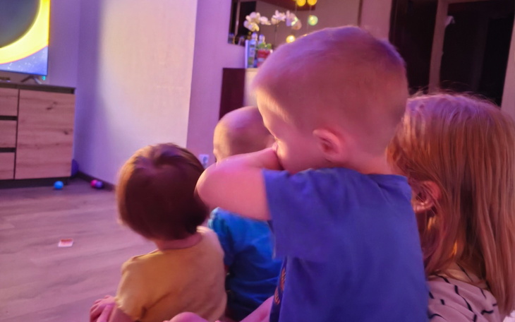 Dzieci siedzące przed telewizorem, oglądające program.