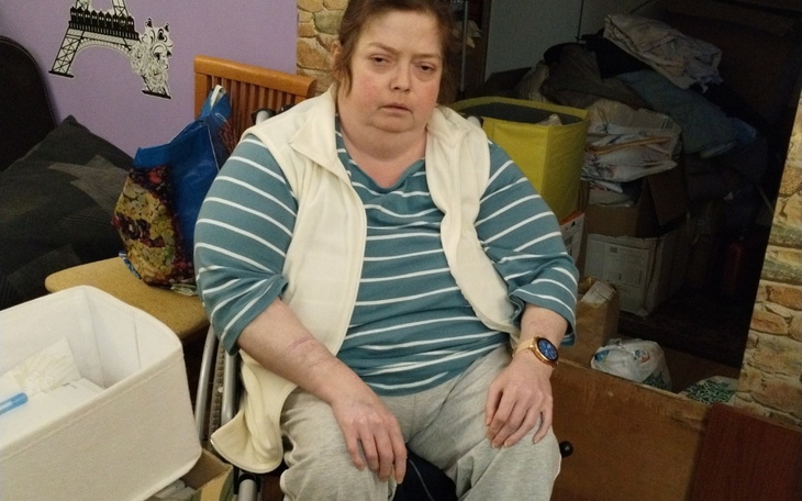 Kobieta siedząca na wózku, z zamyślonym wyrazem twarzy.