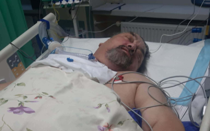 Mężczyzna leżący w szpitalu z monitorami medycznymi.