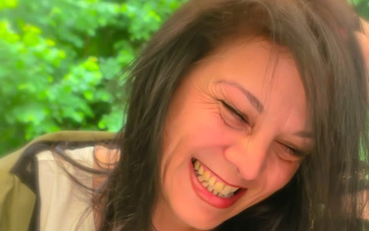 Uśmiechnięta kobieta cieszy się chwilą w otoczeniu zieleni.