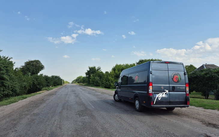 Samochód dostawczy na pustej drodze otoczonej drzewami.