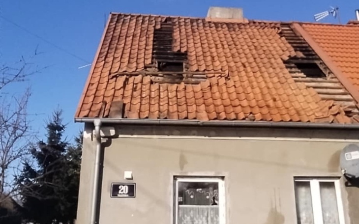 Zniszczony dach domu z widocznymi uszkodzeniami.