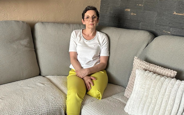 Kobieta siedząca na kanapie w jasnym ubraniu.