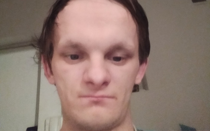 Portret mężczyzny z wyraźnym wyrazem twarzy, w pomieszczeniu.