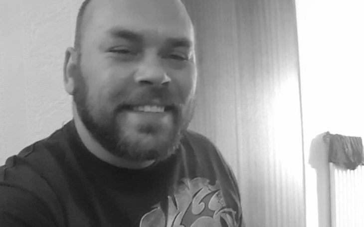 Mężczyzna z uśmiechem, siedzący w jasnym pomieszczeniu.