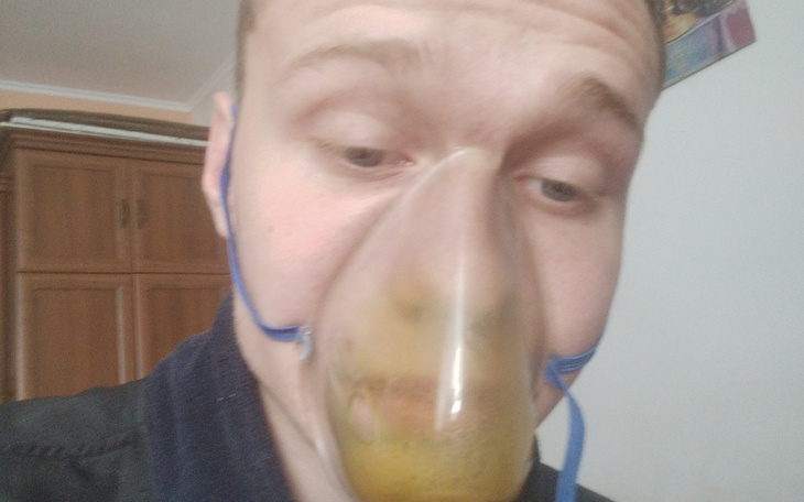 Mężczyzna z maską tlenową, patrzący w kamerę.